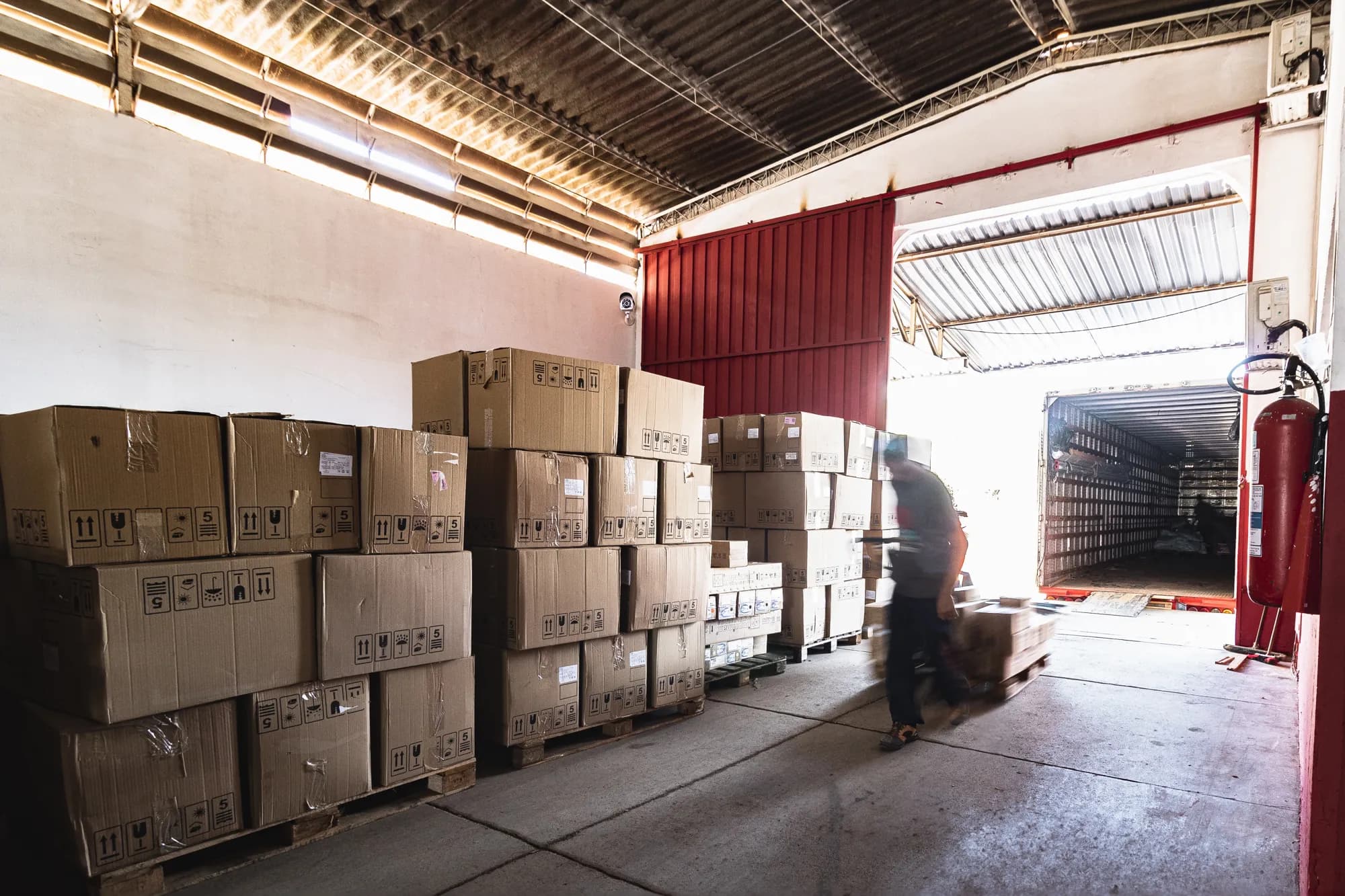 Caixas paletizadas no galpão com carreta encostada na doca para carregamento