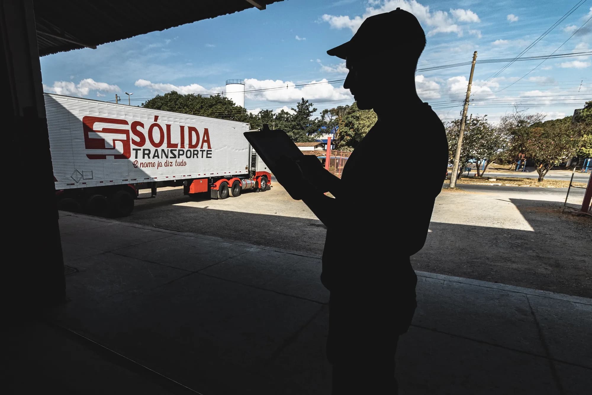Colaborador confere documentos com prancheta diante de uma carreta da Sólida