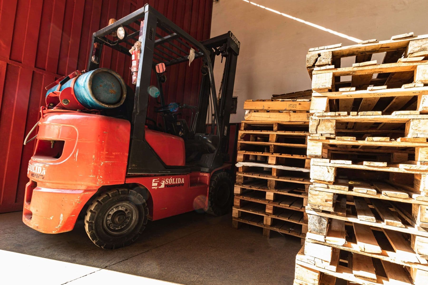 Empilhadeira da Sólida ao lado de pallets de madeira